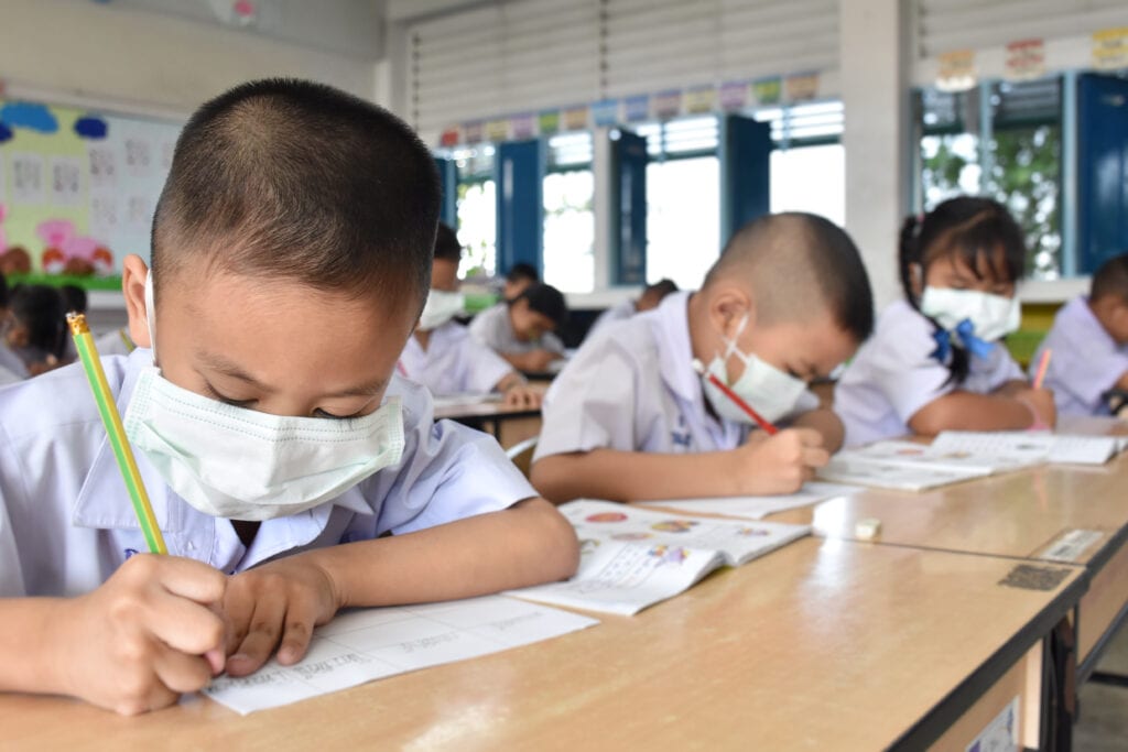 Kids with masks studying in a classroom