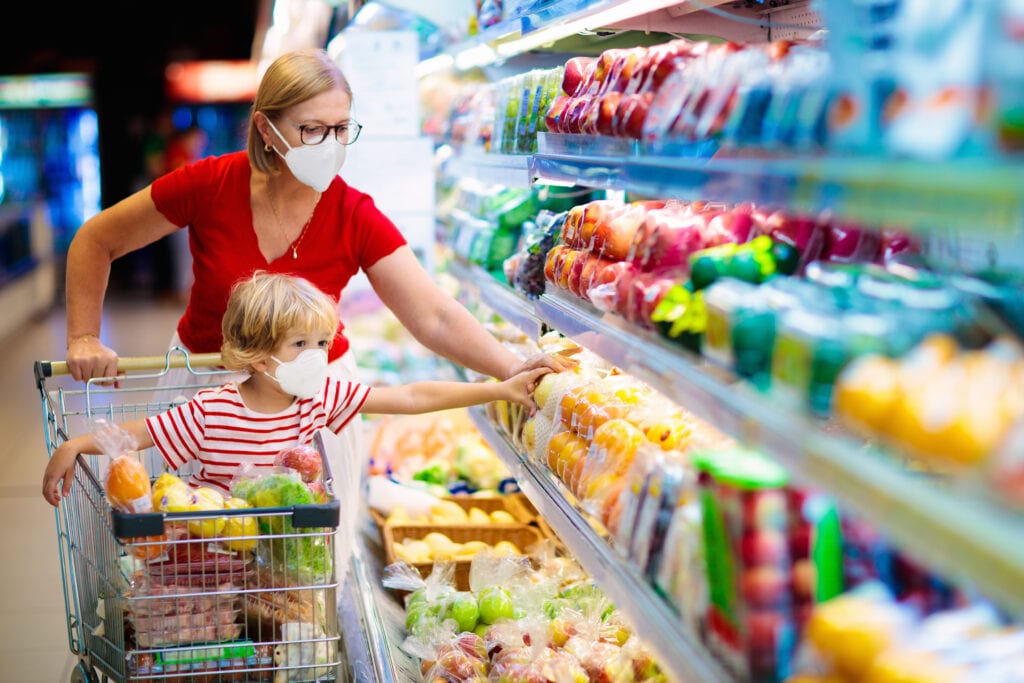 Woman and child with masks shopping for groceries